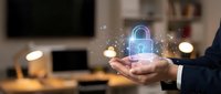 Businessman holding glowing digital padlock with sparkles above palm in modern office environment representing cybersecurity and data protection solutions.