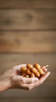 Hand holding skewered longans against wooden background. Fresh tropical fruit in palm, ideal for food, nutrition, and healthy eating concepts.