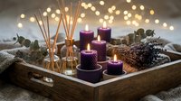 Cozy spa aromatherapy setup with purple candles, reed diffuser and lavender on wooden tray with warm bokeh lights creating relaxing ambiance.