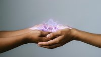 Cupped hands holding glowing pink energy light with magical sparkles and ethereal glow effect against neutral background for spiritual healing concepts.