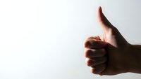Hand showing thumbs up gesture against white background expressing approval, success and positive feedback for business presentations.