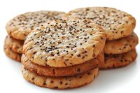 Fresh baked sesame cookies stacked in groups on white background, crispy golden brown butter biscuits with black and white seeds, close up view.