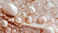 Macro view of water droplets on rose gold surface creating abstract pattern with light reflections. Perfect for luxury cosmetic backgrounds.