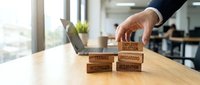 Professional businessman arranging wooden blocks with employee evaluation terms on modern office desk for human resources and performance management.