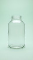 Empty clear glass jar with white label on mint green background, isolated for product packaging and labeling design use.