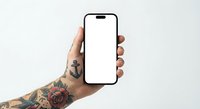 Tattooed hand holding smartphone with blank white screen mockup for app presentation and mobile interface design projects.