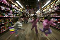 Motion blur captures children rushing through toy store aisle filled with colorful merchandise on shelves, creating dynamic shopping excitement during holiday season.