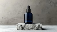 Dark blue glass dropper bottle on rough stone podium against textured gray wall background, minimalist cosmetic product presentation for skincare and beauty packaging.