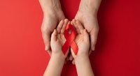 Adult and child hands protecting red ribbon symbol on red background representing HIV AIDS awareness, healthcare support and medical advocacy.