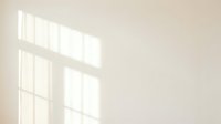 Sunlight streaming through window panes casting geometric shadows on neutral beige wall, creating minimalist interior lighting effect for design and background use.