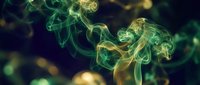 Abstract green and yellow smoke swirls creating ethereal patterns against dark background for creative design projects and artistic compositions.