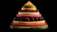 Colorful fruit pyramid with watermelon, kiwi, orange and berries stacked in layers on black background for healthy eating and nutrition concepts.