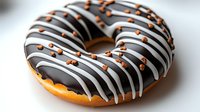 Freshly baked donut covered in dark chocolate glaze with white chocolate drizzle and orange sprinkles on white background, appetizing close-up view for food marketing.
