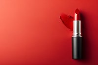 Classic red lipstick with smear mark on vibrant red background. Minimalist beauty product photography highlighting feminine glamour and cosmetic elegance.