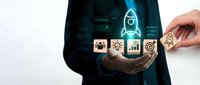 Business professional holding holographic startup icons with rocket launch symbol representing entrepreneurship growth and innovation strategy.