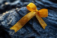 Golden yellow ribbon bow tied on dark textured bark surface with natural lighting creating warm contrast for gift wrapping and decoration concepts.