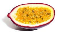 Fresh passion fruit half showing vibrant orange pulp with black seeds isolated on white background for culinary and tropical food designs.