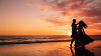Silhouette of a couple dancing on a beach at sunset, man and woman in romantic embrace with golden sky and ocean waves, perfect for wedding, romance, and travel concepts.
