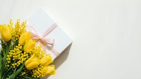 Yellow tulips and mimosa flowers with white gift box tied with pink ribbon on light background for spring celebration and women's day greeting.