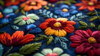 Vibrant embroidered flowers on dark blue fabric with red, orange and mint blooms, decorative floral stitching pattern creates dimensional textile design.