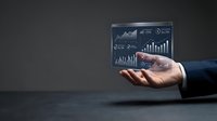 Businessman in dark suit holding digital holographic display with financial charts, graphs and analytics data for business intelligence and investment analysis.