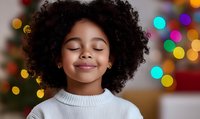 Young African American girl with curly hair smiling peacefully with closed eyes in cozy white sweater against festive Christmas lights bokeh background.