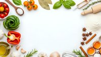 Fresh cooking ingredients frame with vegetables, herbs, spices and pasta on white background. Culinary preparation concept for healthy recipes and meal planning.