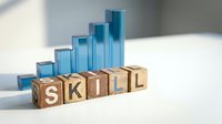 Wooden blocks spelling SKILL with ascending blue bar chart representing professional development and career growth in business training.