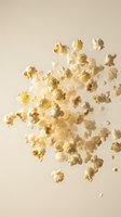 Popped corn kernels scattered in motion against neutral beige background for snack food advertising and cinema entertainment marketing materials.