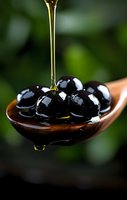 Golden olive oil dripping onto glossy black olives in wooden spoon against dark background with natural bokeh, creating luxurious food composition.