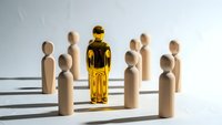 Golden metallic figure standing out among wooden people symbols representing leadership, uniqueness and standing apart from crowd in business concept.