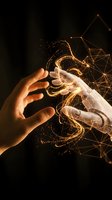 Human hand reaching toward glowing robotic hand with golden light particles and network connections on dark background for AI technology concepts.