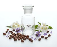 Glass apothecary bottle with jojoba seeds, white jasmine and purple lavender flowers on white background for natural cosmetics concept.