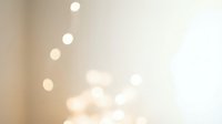Soft blurred bokeh lights creating dreamy atmosphere with warm golden tones and gentle luminous circles on neutral background for elegant design.