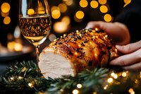 Glazed honey roasted turkey breast with festive bokeh lights and wine glass in background, garnished with pine branches, holiday dinner setting, warm ambient lighting.