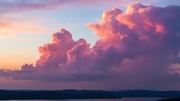 Dramatic sunset clouds in vibrant pink and purple hues over calm ocean horizon creating stunning seascape for nature photography and peaceful backgrounds.
