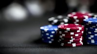 Colorful casino poker chips stacked on dark table with blurred background lights creating atmospheric gambling environment for entertainment industry.