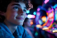 Young teen boy with curly hair looking up with wonder against colorful neon arcade lights and bokeh background creating magical atmosphere of entertainment.