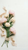 Elegant bouquet of pink peonies and cream ranunculus flowers with silk ribbon on neutral background for wedding invitations and romantic designs.