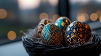 Decorated Easter eggs with intricate geometric patterns and stars in black and turquoise colors resting in dark woven nest against blurred bokeh background.