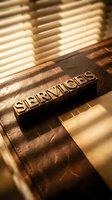Vintage brass letterpress blocks spelling SERVICES on leather surface with warm sunlight shadows, evoking trust and professionalism.