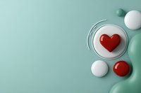 Glossy red heart on a white round platform with mint green background, surrounded by spheres and fluid shapes, copy space.