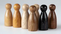 Wooden game pieces in different natural wood tones and colors arranged in row showing diversity and unity concept against light background.
