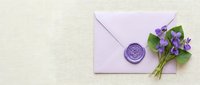Purple envelope with wax seal and violet flowers on beige background for wedding invitations, romantic correspondence and spring greeting cards.