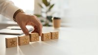 Hand placing wooden blocks with star ratings on white desk for customer feedback and business quality assessment concept.