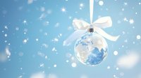 Elegant glass Christmas ornament with world map pattern and white silk bow hanging against soft blue background with bokeh lights and falling snow effect.