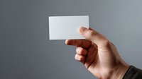 Male hand holding blank white business card against gray background, mockup for branding and corporate identity presentation.