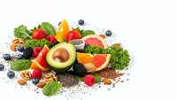 Healthy superfood selection with fresh fruits, vegetables, nuts and seeds arranged on white background for nutritious diet and wellness lifestyle.