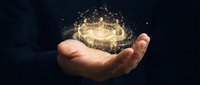 Hand holding glowing golden light particles and sparks against dark background, representing innovation, energy, technology, magic, and future possibilities for business concepts.