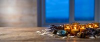 Cozy spa wellness scene with aromatic candles, lavender, stones and natural elements on wooden table creating relaxing atmosphere for meditation and self-care.